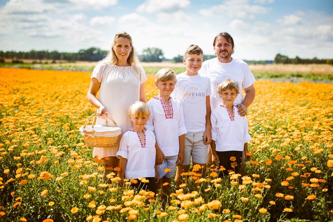 Na fotografii jsou usmívající se rodiče a jejich čtyři synové na poli rozkvetlého oranžového měsíčku. Táta má položenou ruku na rameni jednoho ze synů. Máma drží v ruce košík na sběr bylinek. | © SONNENTOR